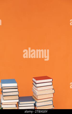 Stacks of educational books in library on orange background Stock Photo