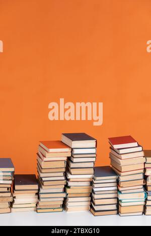 Stacks of educational books in library on orange background Stock Photo