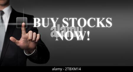 buy stocks now - businessman pressing virtual touchscreen button Stock Photo