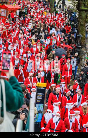 London, UK. 09th Dec, 2023. The santas walk and pose along the South Bank and National Theatre. Hundreds of participants dressed in santa outfits have fun at the annual SantaCon London Christmas parade. The get together, which is non-profit and also collects for charitable causes, sees the cheerful santa revellers go on a walk starting at Leake Street in Waterloo, though parts of London and ending in Trafalgar Square in the evening, taking in various pub-stops and sights along the route. Credit: Imageplotter/Alamy Live News Stock Photo