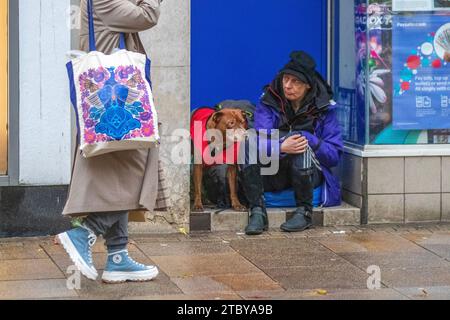 Beggar with dog in Preston, UK. 8 Dec 2023. Sleeping rouigh at Christmas. Shops, shoppers, shopping on a wet day in Fishergate High Street. Stock Photo