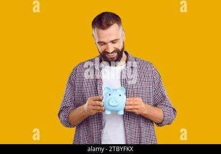 Happy handsome young man holding his piggy bank Stock Photo