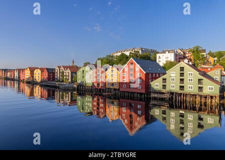 A serene summer evening view of the Nidelva River, illuminated by the setting sun, with iconic wooden houses along the banks in Trondheim, Norway Stock Photo