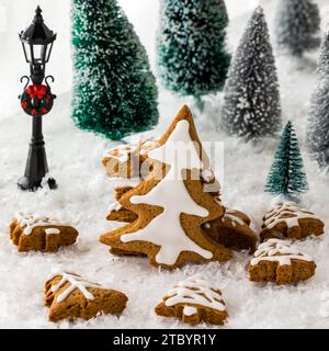 Holiday decorated gingerbread cookie trees amongst trees and snow. Stock Photo