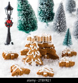 An arrangement of gingerbread cookie trees surrounded by trees and snow. Stock Photo