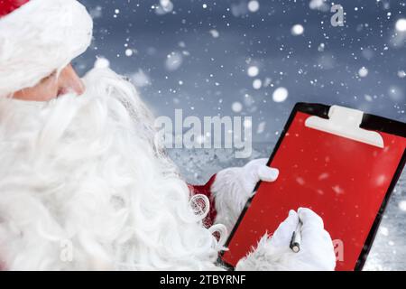 Close-up portrait of a young Santa Claus writing notes on the red paper Stock Photo