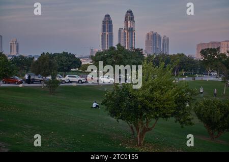 UDC tower and the pearl skyline , from Katara hills in Doha, Qatar sunset shot with trees in foreground and clouds in the sky in background Stock Photo