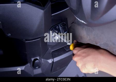 a man breaks a motorcycle starter hole with a screwdriver, honda beat brand motorcycle theft concept Stock Photo