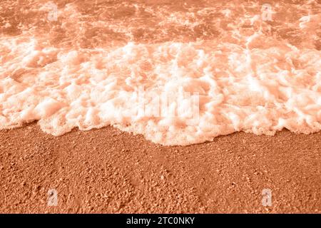 Sea foam on the beach, top view. Demonstrating color of 2024 year Peach Fuzz. Stock Photo