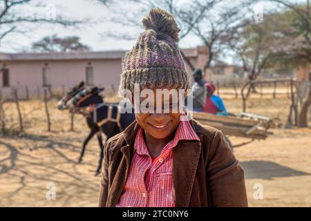 portrait of happy village young woman wearing a beanie with a mischievous look, donkey cart in the background ,botswana rural area Stock Photo