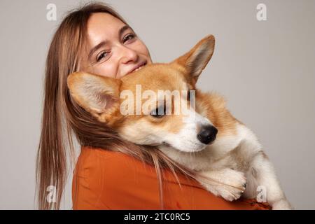 girl holding a corgi dog in her arms on a clean light background, love for dogs Stock Photo