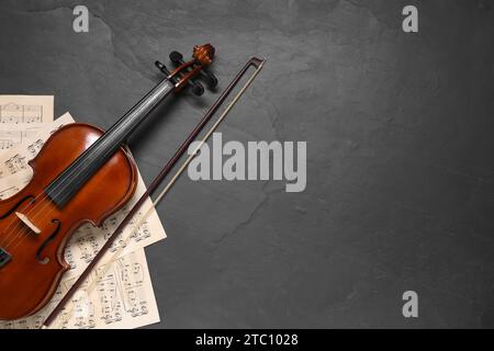 Violin, bow and music sheets on black table, top view. Space for text Stock Photo