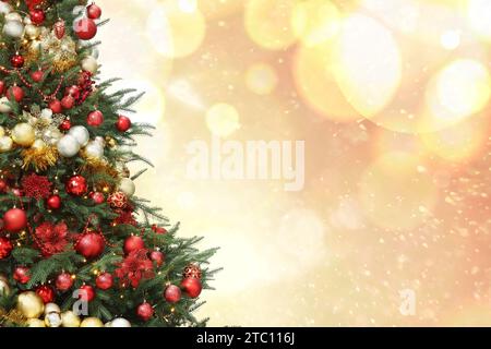 Christmas tree decorated with red and golden festive balls against blurred background, bokeh effect. Space for text Stock Photo