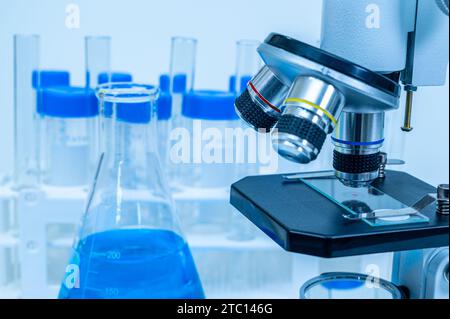 A close-up of a blue liquid erlenmeyer flask and microscope Stock Photo