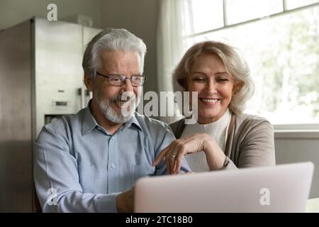 Loving retired spouses watch comedy movie on laptop screen Stock Photo
