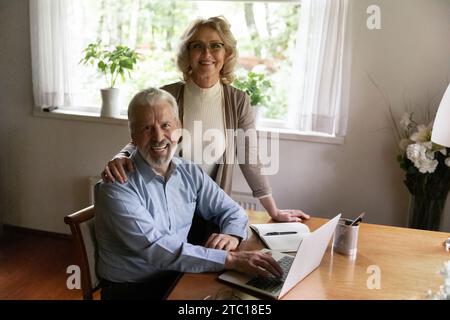 Portrait of happy senior spouses managing family business using laptop Stock Photo