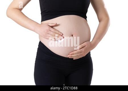 A pregnant woman is applying stretch mark cream on her belly Stock Photo