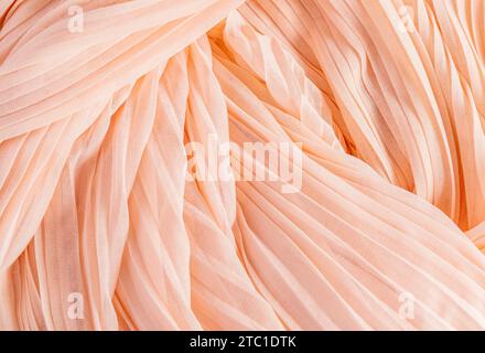 Elegant peach, silk or chiffon fabric texture. Festive background for design. layout. A copy space. Color of the Year 2024 Peach Fuzz Stock Photo