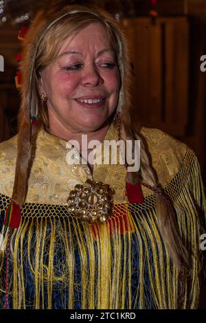 Saariselka, Finland - November 29, 2010: Sami woman in traditional dress in a Sami 'kota' used to host a dinner event for tourists. Stock Photo