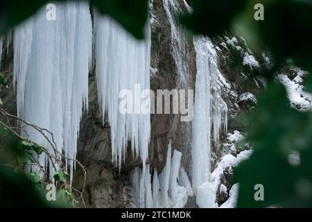 Icicles waterfall. Freezing of water in the river in winter. Majestic icicles hang from the cliff face. Cold winter texture. Atmospheric natural backg Stock Photo