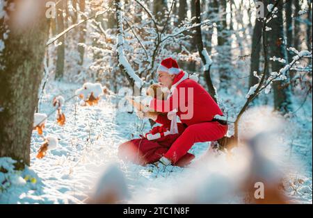 Christmas Santa reading letter near the Christmas nature background. Funny Santa in Santa hat read letter over winter nature background. Stock Photo