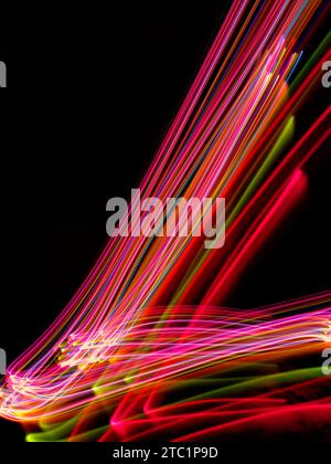 Long exposure light trails of pink, orange, yellow and blue light Stock Photo