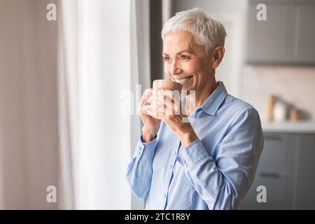 Relaxed smiling mature woman drinking coffee at home Stock Photo