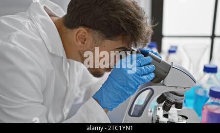 Young arab man scientist using microscope at laboratory Stock Photo