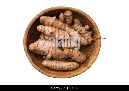 Whole curcuma roots in bowl. Fresh raw turmeric spice, isolated on white. Top view, flat lay. Stock Photo