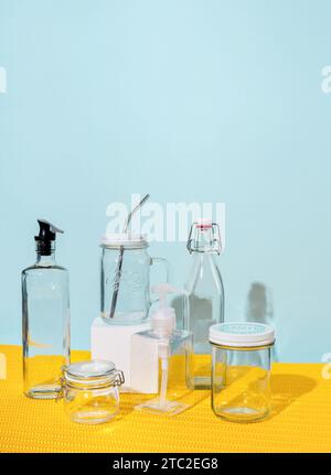 Glass containers and water bottles lie on a yellow and mint background Stock Photo