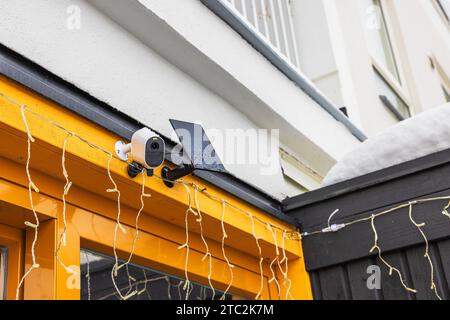 Close-up view of exterior surveillance camera equipped with solar panel installed on facade of villa on frosty winter day. Stock Photo