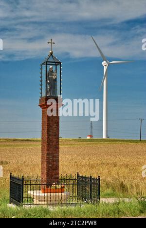 Roadside shrine and wind turbine at field of grain near Puck, Pomorskie, Poland Stock Photo