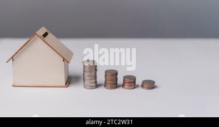 Stacked of Coins and House Model. Business investment and saving money finance, tax Interest rates for loans and real estate prices concept. Stock Photo