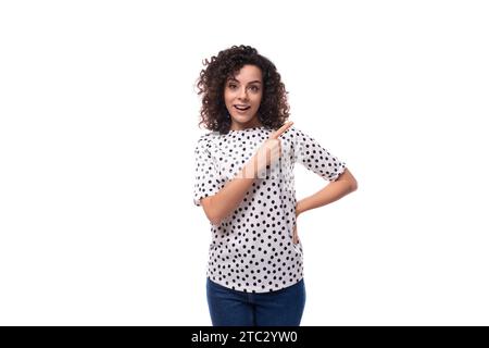 young dark-haired caucasian woman dressed in a blouse points with her hands space for advertising Stock Photo