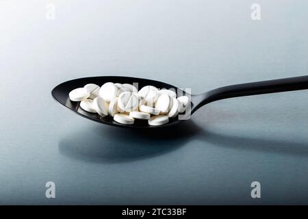White pill tablets on a black spoon Stock Photo