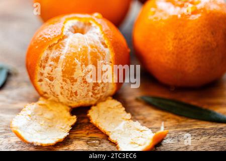 Still life of three fresh mandarins, one of them half peeled. Stock Photo