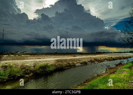Dramatic dark storm clouds with pouring rain over rural landscape Stock Photo
