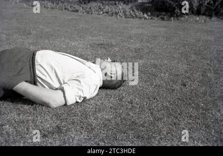 1950s, historical, summertime and a middle-age man, rolled up sleeeves, chiiling out, lying on his back on an area of grass, England, UK. Stock Photo