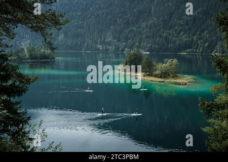 View through the trees of the Eibsee lake at sunrise, Eibsee, Bavaria ...