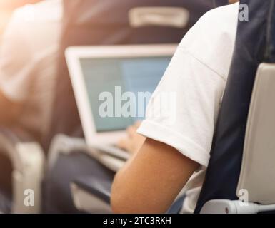 Man working with his white laptop on aircraft board during the flight Stock Photo