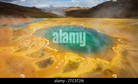 A high-resolution image of a geothermal area featuring bubbling hot springs surrounded by lush vegetation and rocky terrain Stock Photo