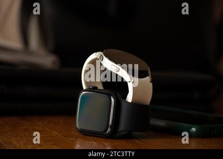 Dnipro, Ukraine - December 10, 2023: White smart watches Samsung Galaxy Active and Apple Watch Series 8 lie on the table at home, two smart watches Stock Photo
