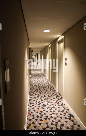 Long interior corridor in a hotel, with patterned carpet consisting of triangles Stock Photo