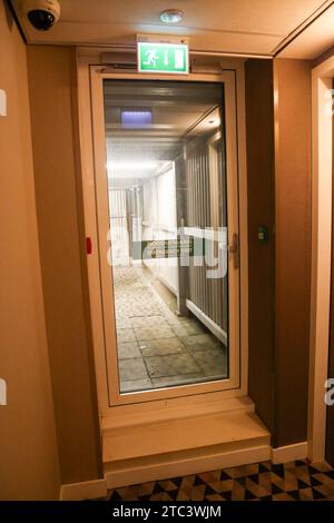 Emergency exit, glass door towards outside corridor, with exit sign above it Stock Photo