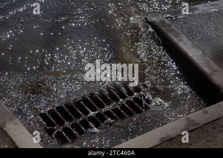 Flow of water during heavy rain and clogging of street sewage. The flow of water during a strong hurricane in storm sewers. Sewage storm system along Stock Photo