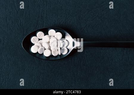 White pill tablets on a black spoon Stock Photo