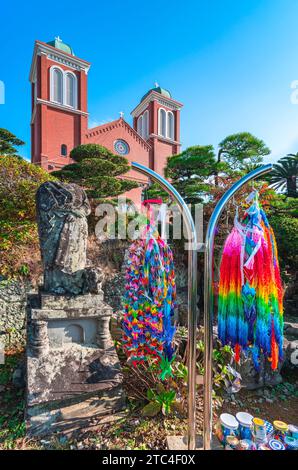 nagasaki, kyushu - dec 11 2023: A-bombed remain of the former Urakami Cathedral aside a thousand cranes origami decorations with the brick facade of t Stock Photo