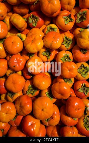 Harvest of ripe whole persimmons Stock Photo