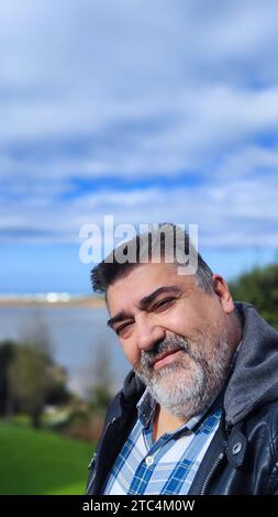 bearded man taking a selfie with the beach in the background and copy space Stock Photo
