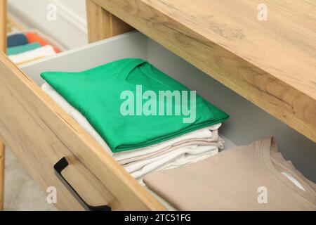 Stacks of different folded shirts in drawer indoors. Organizing clothes Stock Photo